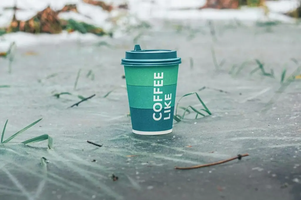 Eco-friendly coffee cup on icy surface with winter backdrop, perfect for a chilly coffee break.