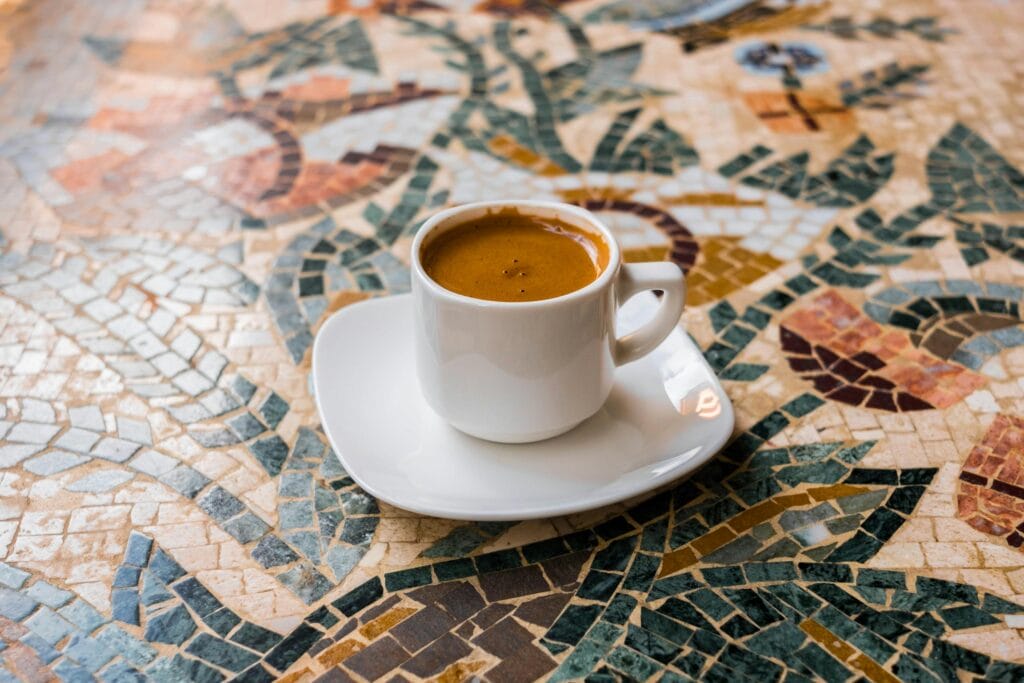 White espresso cup on a vibrant mosaic table, perfect for coffee enthusiasts.